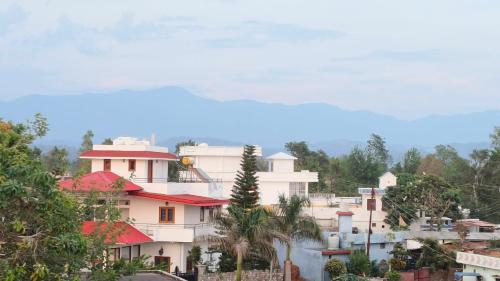 un groupe de bâtiments sur une colline plantée d'arbres dans l'établissement LDS Homestay, à Rāmnagar