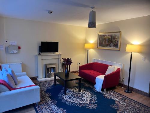 a living room with a red couch and a fireplace at Prestashortstays in Belfast