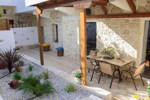 a patio with a table and chairs and a stone wall at Villa Agapi 2 in Kamilari
