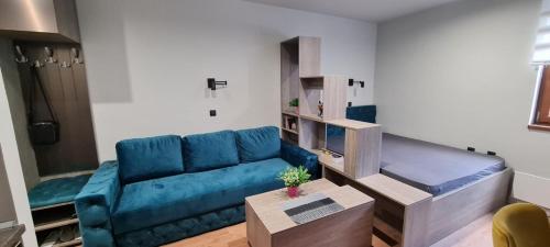 sala de estar con sofá azul y mesa en Apartman Snezni Vrh - Bela Reka, Brzece, en Brzeće