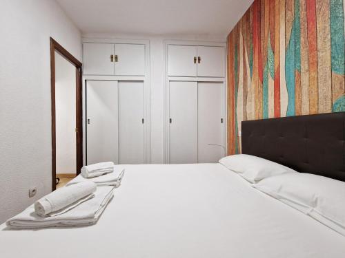 a white bed in a room with white cabinets at Calle Mayor, alójate en el centro histórico de Madrid in Madrid