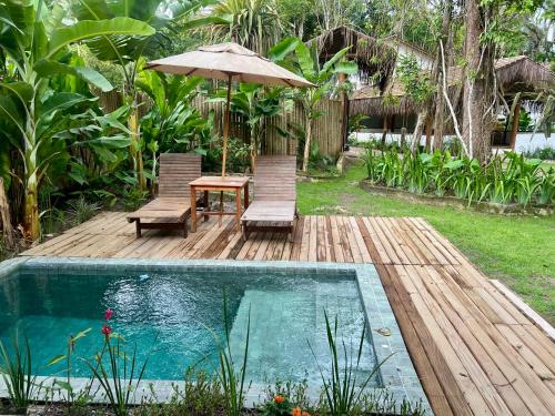 a patio with a table and an umbrella and a pool at Villa Sagui Trancoso in Trancoso