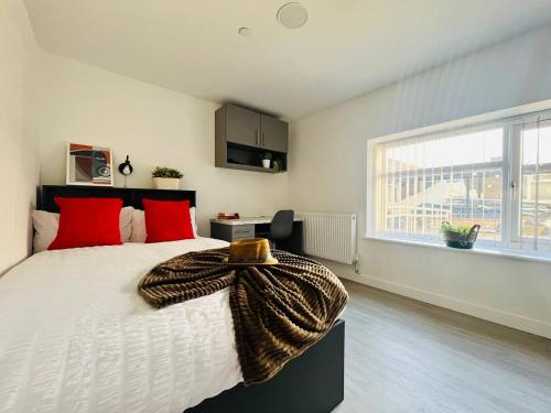 um quarto com uma cama grande com almofadas vermelhas e uma janela em Chic Hideaway: Modern Studio in Stretford em Manchester