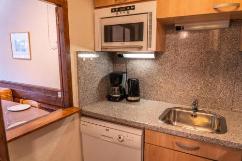 une cuisine avec un évier et un micro-ondes dans l'établissement Résidence Le Belvedere - Studio coin nuit au coeur des Orres 1650 MAE-6264, aux Orres