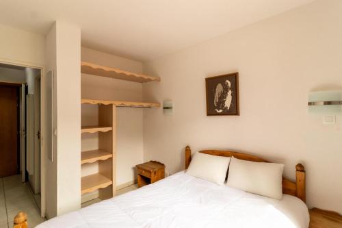 1 dormitorio con cama y estante para libros en Résidence Le Balcon Des Airelles - 2 Pièces pour 4 Personnes 344, en Les Orres