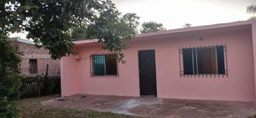 una casa rosa con una puerta negra y ventanas en Mburucuya casa en Mburucuyá