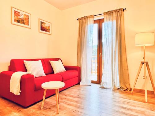 um sofá vermelho numa sala de estar com uma janela em La casa del Mercato em Santa Maria Maggiore