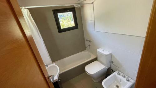 a bathroom with a toilet and a tub and a sink at Loretta - Sumando Latitudes in San Martín de los Andes
