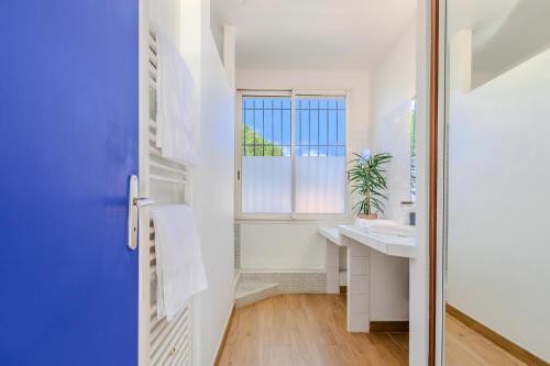een witte badkamer met een wastafel en een raam bij L'oranger - Villa avec piscine in Saint-Jean-de-Védas