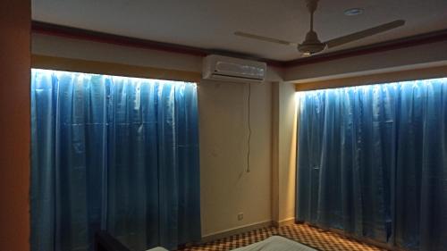 ダッカにあるSignature Homeの青いカーテンとファンが備わる客室です。