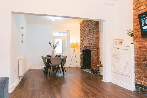 a living room with a table and a brick wall at Mideyah Stays - 3 Bed Comfy House in Cardiff