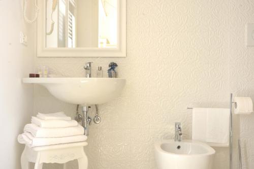 a white bathroom with a sink and a mirror at Dimora storica Santasofia a Martano in Martano