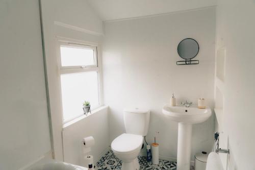 Baño blanco con aseo y lavamanos en Mideyah Stays - 3 Bed Comfy House, en Cardiff