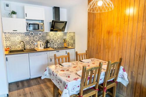 une cuisine avec une table et des chaises ainsi qu'une cuisine avec une cuisinière dans l'établissement Résidence Le Balcon Des Airelles - Appartement calme au coeur des Orres 1800 MAE-6694, aux Orres