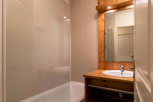 uma casa de banho com um lavatório e um chuveiro com um espelho. em Résidence Le Balcon Des Airelles - 2 Pièces pour 4 Personnes 634 em Les Orres