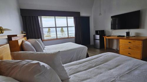 a hotel room with two beds and a flat screen tv at Hébergement Fort Prével in Saint-Georges-de-Malbaie