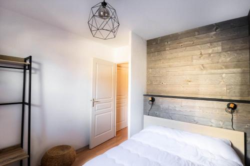- une chambre avec un mur en bois et un lit dans l'établissement Résidence Les Terrasses Du Soleil D'or - Charmant appartement au pied des pistes MAE-6734, aux Orres