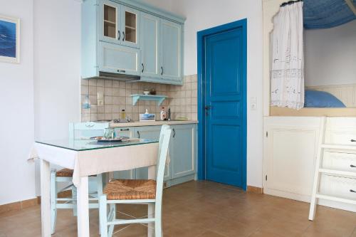 a kitchen with blue cabinets and a blue door at Vicky's Studios in Órmos Aiyialís