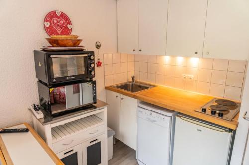 une petite cuisine avec un micro-ondes et un évier dans l'établissement Résidence Le Boussolenc - Studio vue pistes plein coeur des Orres 1650 MAE-6924, aux Orres