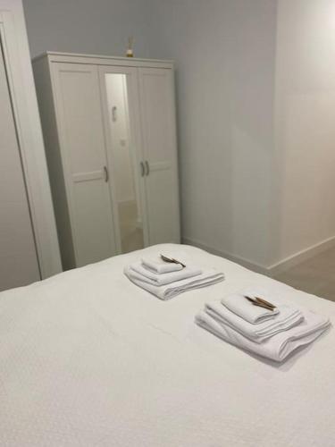 2 toallas blancas plegadas en una cama frente a un espejo en Apartamento Baeza 4A en Baeza