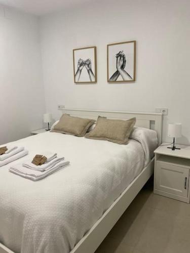 a bedroom with a white bed with three pictures on the wall at Apartamento Baeza 4A in Baeza