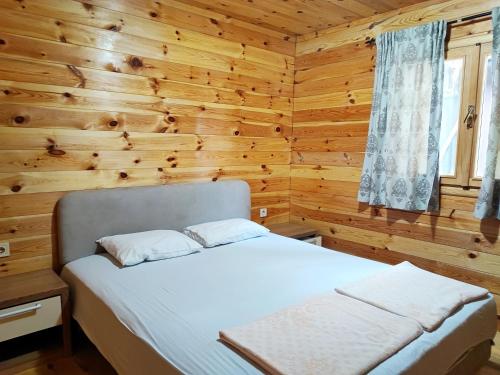 - une chambre avec un lit dans un mur en bois dans l'établissement Coso House Ada Bojana, à Ulcinj