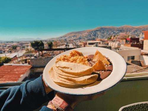 a person holding a plate of food with a sandwich at Viajero Oaxaca Hostel in Oaxaca City