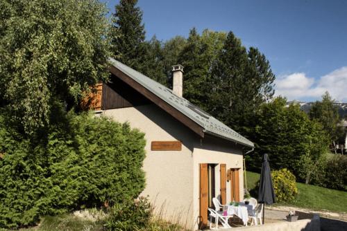 ein kleines weißes Gebäude mit Kamin und einigen Bäumen in der Unterkunft Résidence Le Petit Nid - Maisons & Villas pour 7 Personnes 324 in Corrençon-en-Vercors