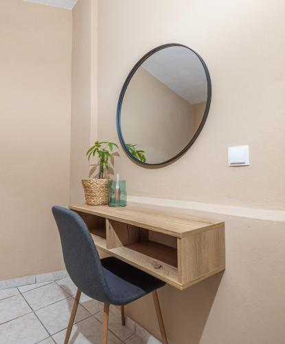 a mirror on a wall next to a desk and a chair at Sarita's Apartments & Suite in Laganas