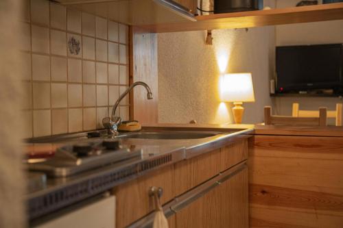 a kitchen with a sink and a stove and a lamp at Résidence Le Pouzenc - Studio pour 6 Personnes 424 in Les Orres