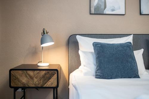 a bed with a blue pillow and a lamp on a table at Zentrale Design Wohnung in Ufernähe - 105 qm - Parkplatz - Küche - Netflix in Bingen am Rhein