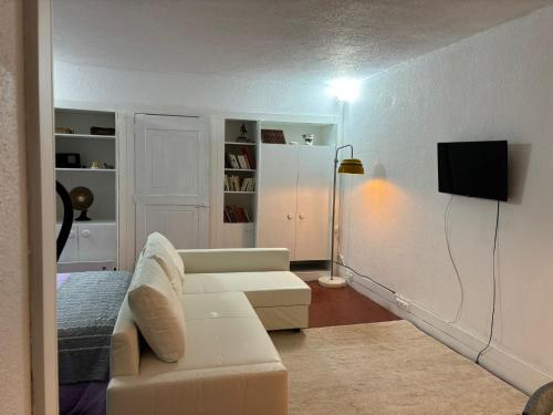 uma sala de estar com um sofá branco e uma televisão em TROIAMAR em Tróia