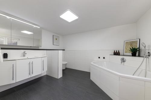 a white bathroom with a tub and a sink at Zentrale Design Wohnung in Ufernähe - 105 qm - Parkplatz - Küche - Netflix in Bingen am Rhein