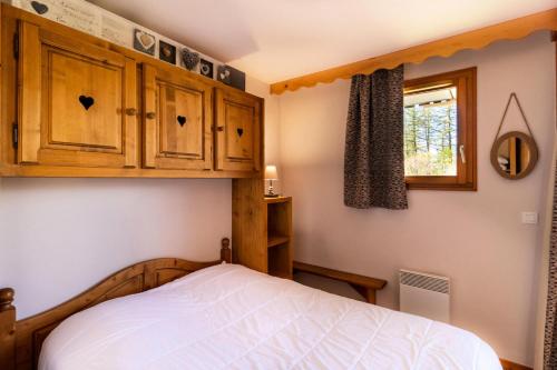 - une chambre avec un lit, des armoires en bois et une fenêtre dans l'établissement Résidence Les Hauts De Preclaux - Appartement agréable au pied des pistes. MAE-9464, aux Orres