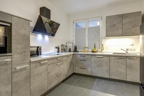 a large kitchen with stainless steel appliances and gray cabinets at Zentrale Design Wohnung in Ufernähe - 105 qm - Parkplatz - Küche - Netflix in Bingen am Rhein