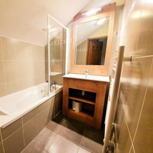 une salle de bain avec un lavabo, une baignoire et un miroir dans l'établissement Les Chalets Des Rennes - Appartement cozy 3 pièces - Les Chalets Des Rennes MAE-9474, à Vars