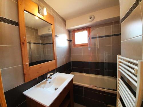 une salle de bain avec un lavabo, un miroir et une baignoire dans l'établissement Les Chalets Des Rennes - Appartement 2 pièces - Les Chalets Des Rennes MAE-9534, à Vars