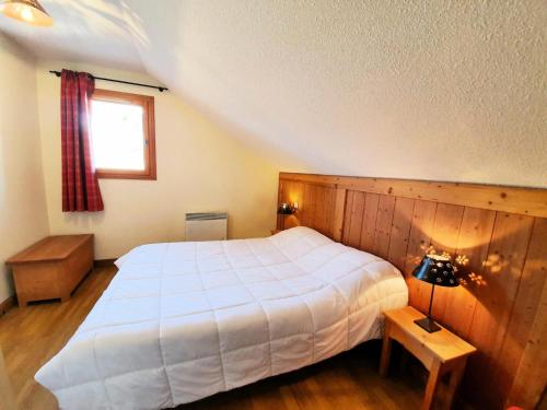 een slaapkamer met een wit bed en een raam bij Les Chalets Des Rennes - 3 Pièces pour 6 Personnes 604 in Vars