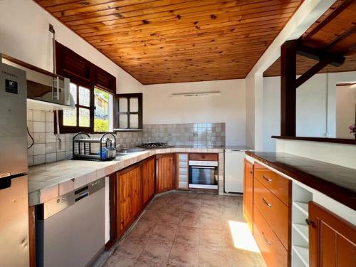 a large kitchen with wooden ceilings and wooden counters at VILLA DES PALMIERS in Le Marin