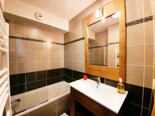 une salle de bain avec un lavabo, une baignoire et un miroir dans l'établissement Les Chalets Des Rennes - Appartement cosy 2 pièces - Les Chalets Des Rennes MAE-9564, à Vars