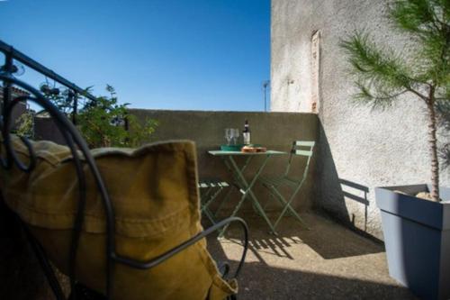 einen Balkon mit einem Tisch und einer Flasche Wein in der Unterkunft Lovely house with courtyard and terrace near canal du Midi in Trèbes