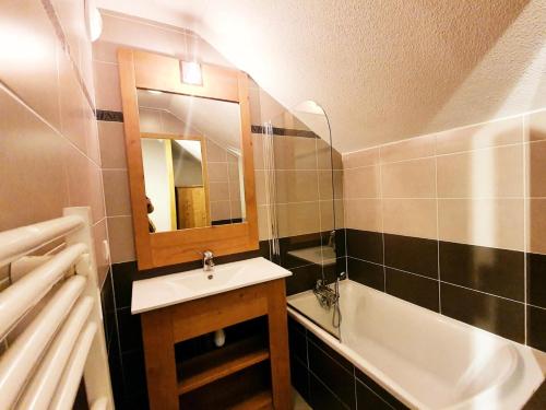 une salle de bain avec un lavabo, une baignoire et un miroir dans l'établissement Les Chalets Des Rennes - Appartement 6 personnes - Les Chalets Des Rennes MAE-9644, à Vars