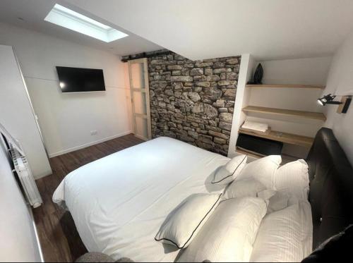a bedroom with a large white bed with a stone wall at Eiffel Tour - Cosy Manéo in Paris