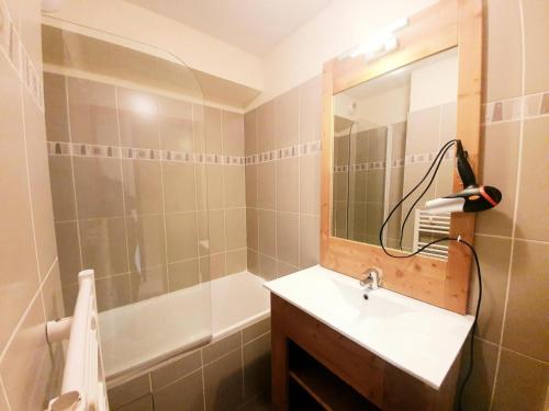 een badkamer met een wastafel, een douche en een spiegel bij Les Chalets Des Rennes - 2 Pièces pour 4 Personnes 734 in Vars