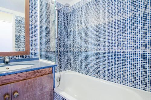 La salle de bains est pourvue de carrelage bleu, d'une baignoire et d'un lavabo. dans l'établissement Résidence le Hameau de Cap Esterel - maeva Home - Appartement climatisé 2 Pièces 5 Personnes Confort - vue mer MAE-5833, à Saint-Raphaël