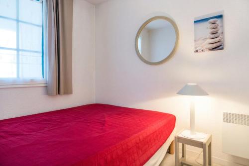 um quarto com uma cama vermelha e um espelho em Résidence Port Bourgenay - maeva Home - 2 Pièces 5 Personnes Confort 65 em Talmont