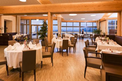 a restaurant with white tables and chairs and a person in the background at Heilmoorbad Schwanberg in Schwanberg