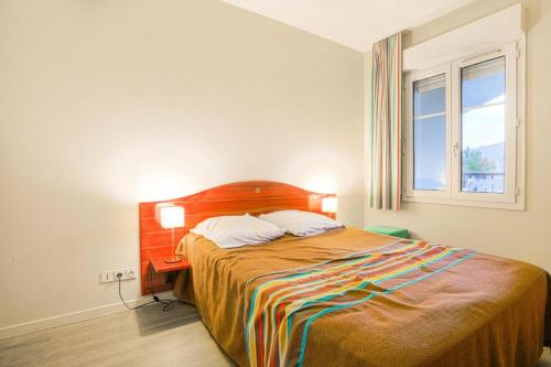 een slaapkamer met een bed met een houten hoofdeinde en een raam bij Résidence Port Guillaume - maeva Home - 2 Pièces 4 Personnes Sélection 88 in Dives-sur-Mer