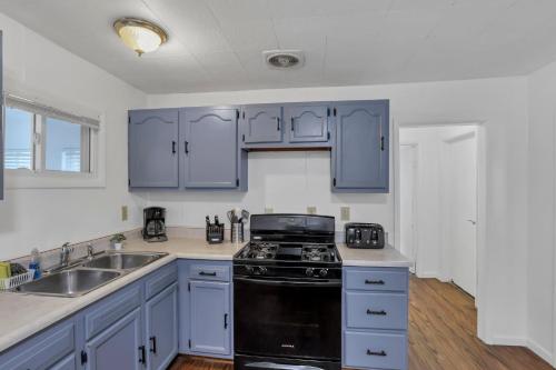 a kitchen with blue cabinets and a black stove at Housepitality - The Southside Ranch in Columbus