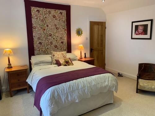 a bedroom with a large bed and two tables and two lamps at Stable Cottage in Tettenhall